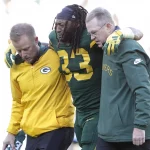 FootballR - NFL - Packers RB Aaron Jones wird nach einem Spiel gegen die Chargers vom Feld geholfen.