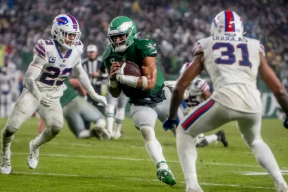 FootballR - NFL - Der Eagles QB Jalen Hurts läuft mit dem Ball auf einem Feld.