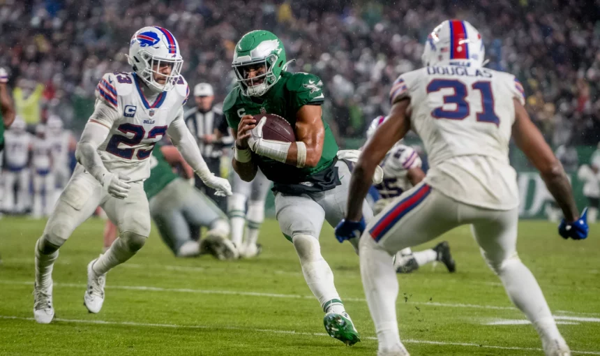 FootballR - NFL - Der Eagles QB Jalen Hurts läuft mit dem Ball auf einem Feld.