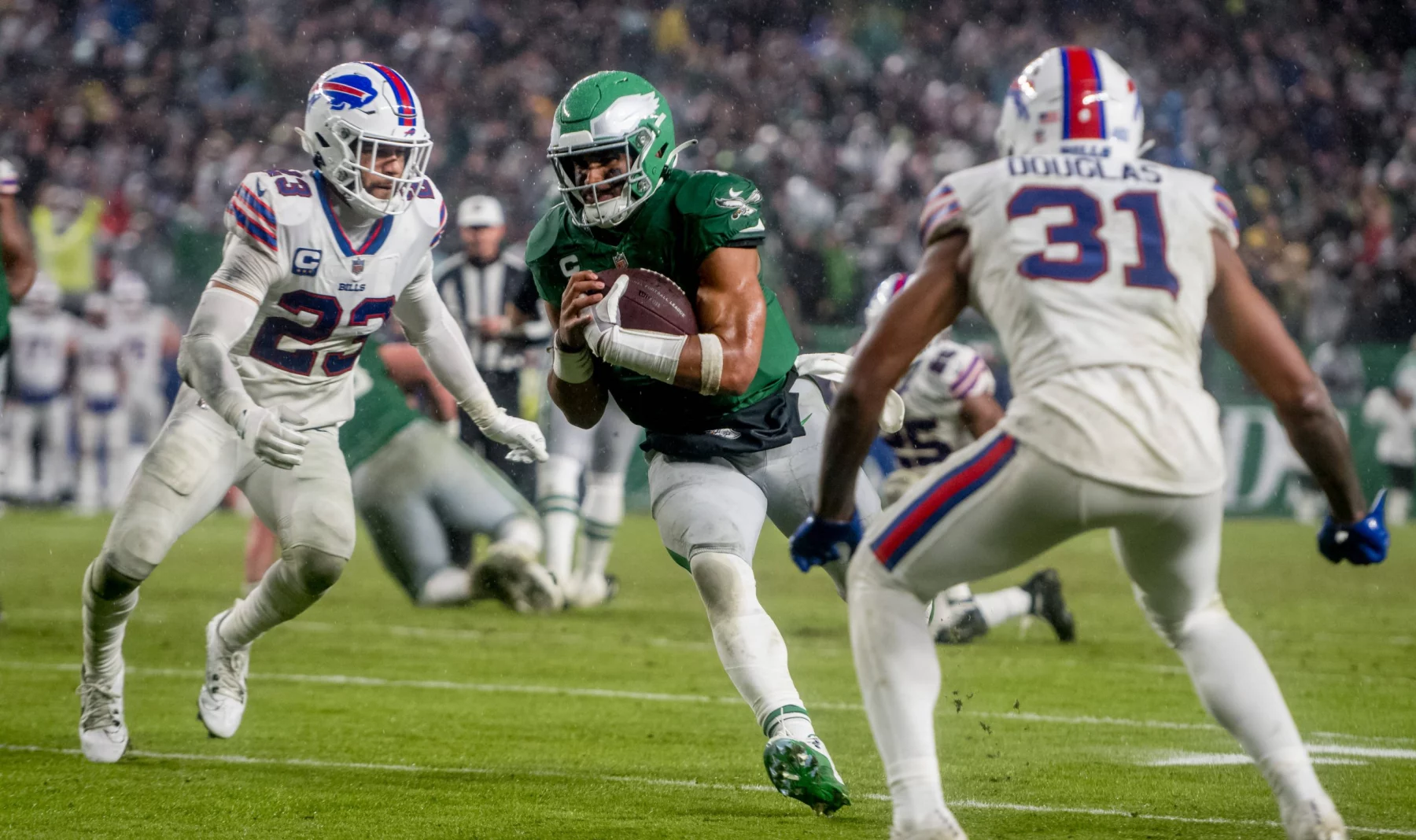 FootballR - NFL - Der Eagles QB Jalen Hurts läuft mit dem Ball auf einem Feld.