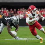 FootballR - NFL - ein Footballspieler der Kansas City Chiefs, weicht gekonnt der Verteidigung der Raiders, Marcus Peters, aus, indem er furchtlos mit dem Ball nach vorne prescht.