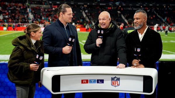 FootballR - RTL NFL - Eine Gruppe von Menschen steht vor einem NFL-Footballfeld.