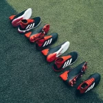 FootballR - NFL - Eine Gruppe Fußballschuhe steht aufgereiht auf einem Rasenplatz.