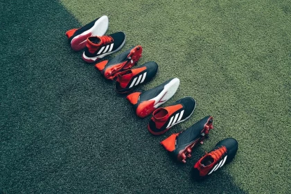 FootballR - NFL - Eine Gruppe Fußballschuhe steht aufgereiht auf einem Rasenplatz.