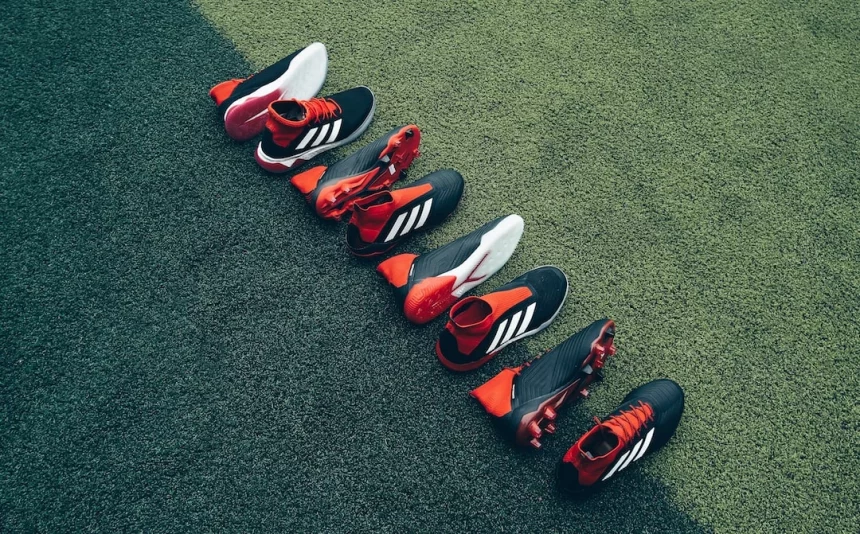 FootballR - NFL - Eine Gruppe Fußballschuhe steht aufgereiht auf einem Rasenplatz.