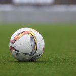 FootballR - NFL - Ein Fußball liegt auf einem grünen Feld.