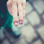 FootballR - NFL - Der Finger eines Kindes mit einem roten Fleck darauf.