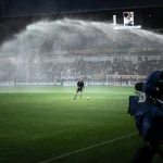 FootballR - NFL - Ein Fußballspieler wird auf einem Fußballfeld mit Wasser besprüht.