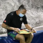 FootballR - NFL - Ein Mann mit Gesichtsmaske sitzt auf einer Bank.