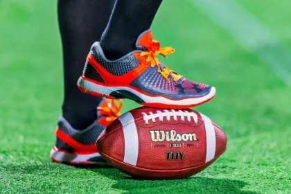 FootballR - NFL - Die Füße einer Person stehen auf einem Fußball.