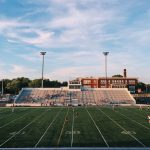 FootballR - NFL - Ein leeres Fußballfeld mit Leuten, die Fußball spielen.