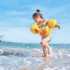 FootballR - NFL - Ein kleines Mädchen, das mit einer gelben Schwimmweste im Meer spielt.