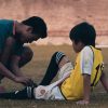 FootballR - NFL - Ein Mann hilft einem kleinen Jungen mit einem Fußball.