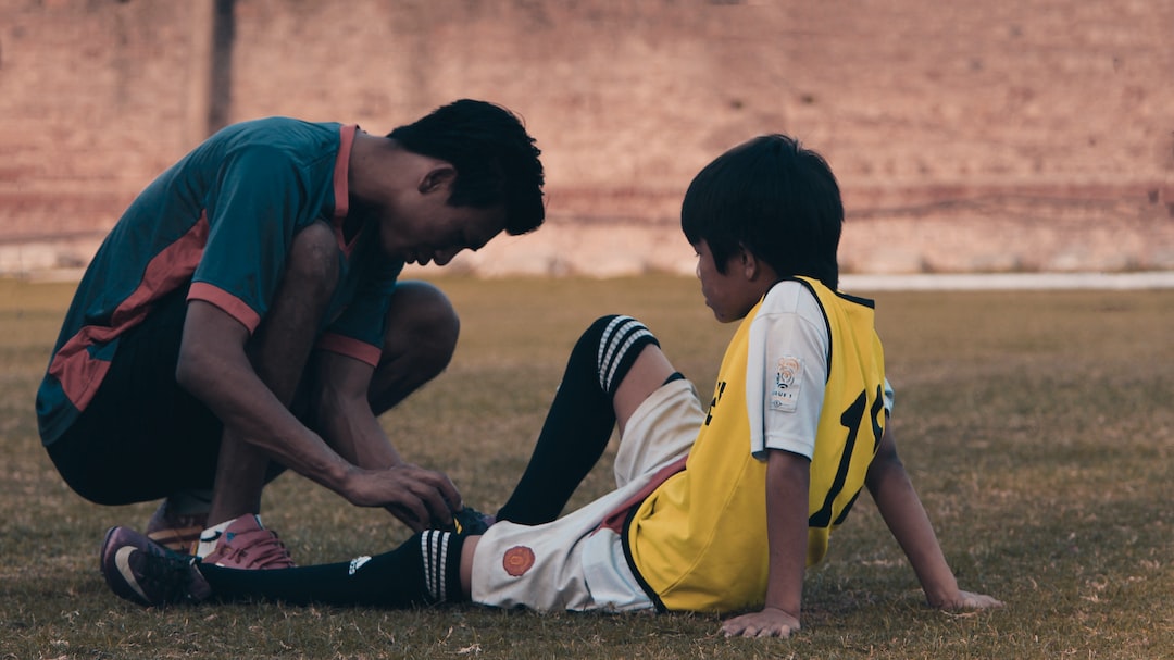 FootballR - NFL - Ein Mann hilft einem kleinen Jungen mit einem Fußball.