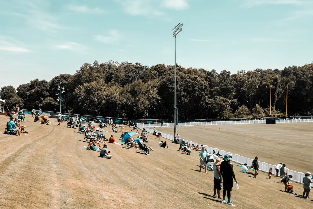 FootballR - NFL - Eine Gruppe von Menschen sitzt auf dem Rasen eines Baseballfeldes.