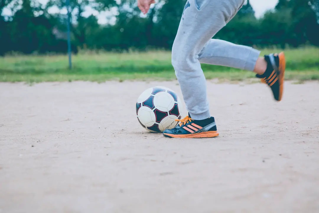 FootballR - NFL - Ein Junge kickt einen Fußball auf einem unbefestigten Feld.