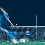 FootballR - NFL - Ein Fußballspieler kickt nachts den Ball.