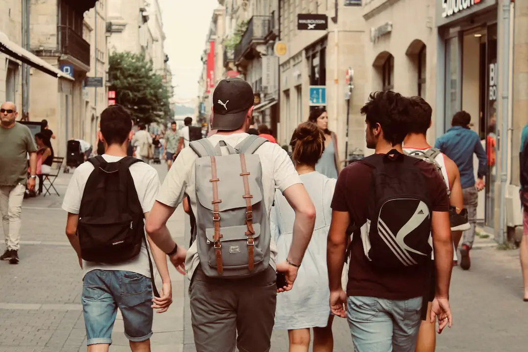 FootballR - NFL - Eine Gruppe von Menschen geht mit Rucksäcken eine Straße entlang.