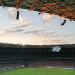 FootballR - NFL - Ein Fußballspiel in einem Stadion bei Sonnenuntergang.