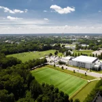 FootballR - NFL - Eine Luftaufnahme eines Campus mit einem Fußballfeld und Bäumen.