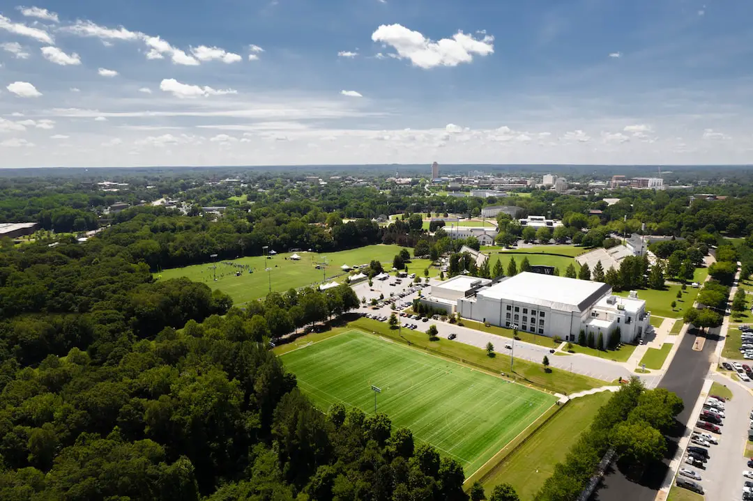 FootballR - NFL - Eine Luftaufnahme eines Campus mit einem Fußballfeld und Bäumen.
