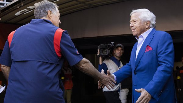 FootballR - NFL - Robert Kraft, der Besitzer der New England Patriots, schüttelt Bill Belichick, dem Cheftrainer des Teams, die Hand, beide in ihren charakteristischen blauen Anzügen.