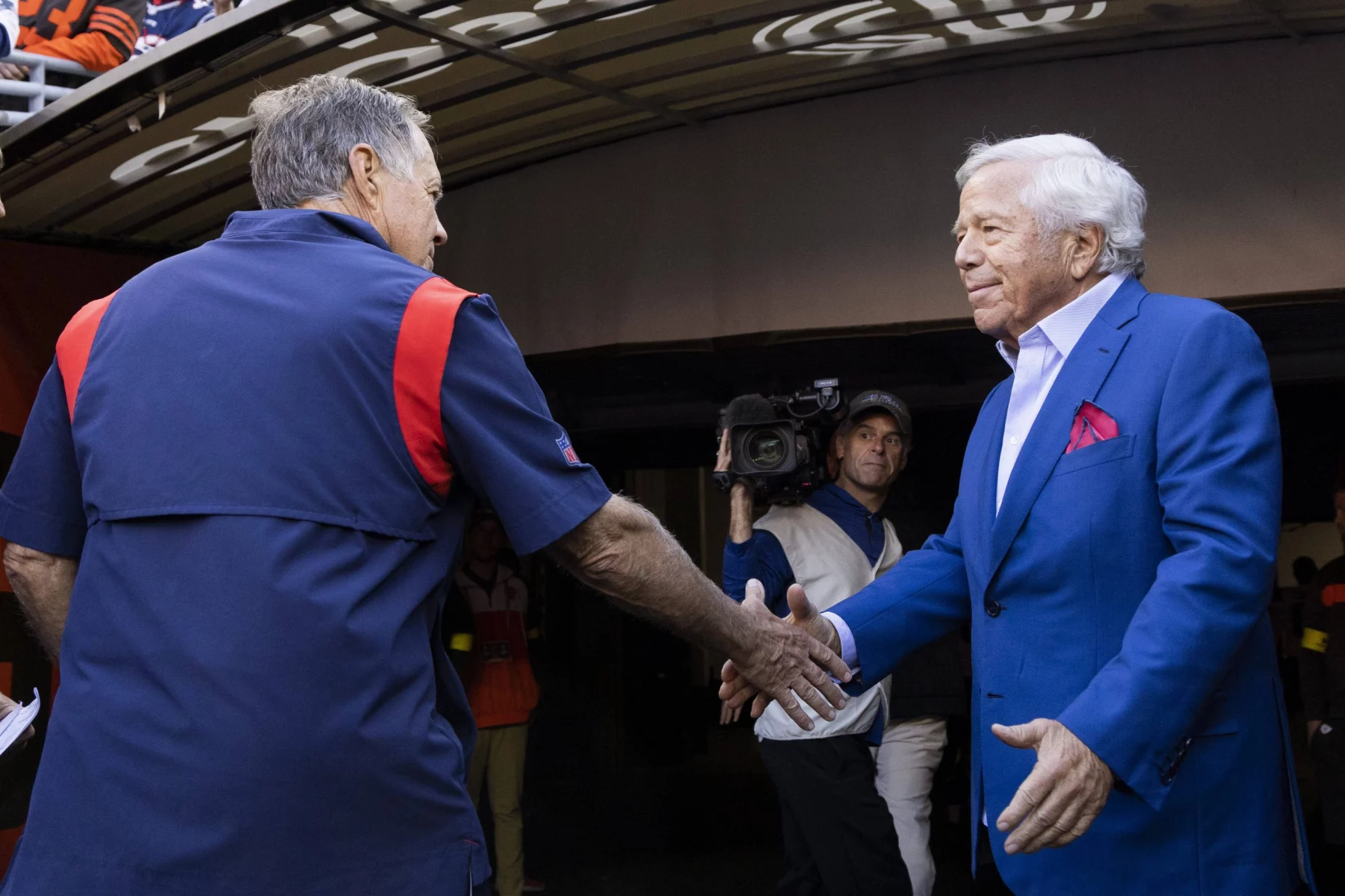 FootballR - NFL - Robert Kraft, der Besitzer der New England Patriots, schüttelt Bill Belichick, dem Cheftrainer des Teams, die Hand, beide in ihren charakteristischen blauen Anzügen.