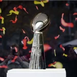 FootballR - NFL - Die Super Bowl-Trophäe wird stolz inmitten eines Konfetti-Meeres präsentiert und symbolisiert die Siegesfeier des Super Bowl 2027 am Austragungsort.