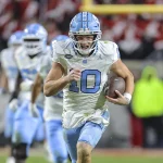 FootballR - NFL - Drake Maye, ein Quarterback im NFL Draft, läuft mit dem Ball.