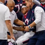 FootballR - NFL - Tank Dell - Einem Spieler der Houston Texans wird vom Feld geholfen, nachdem er einen schweren Rückschlag, insbesondere einen Wadenbeinbruch, erlitten hat.
