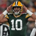 FootballR - NFL Quarterbacks - Ein Spieler der Green Bay Packers, Quarterback Jordan Love, hält während eines Spiels, möglicherweise in den Playoffs, die Hände hoch.