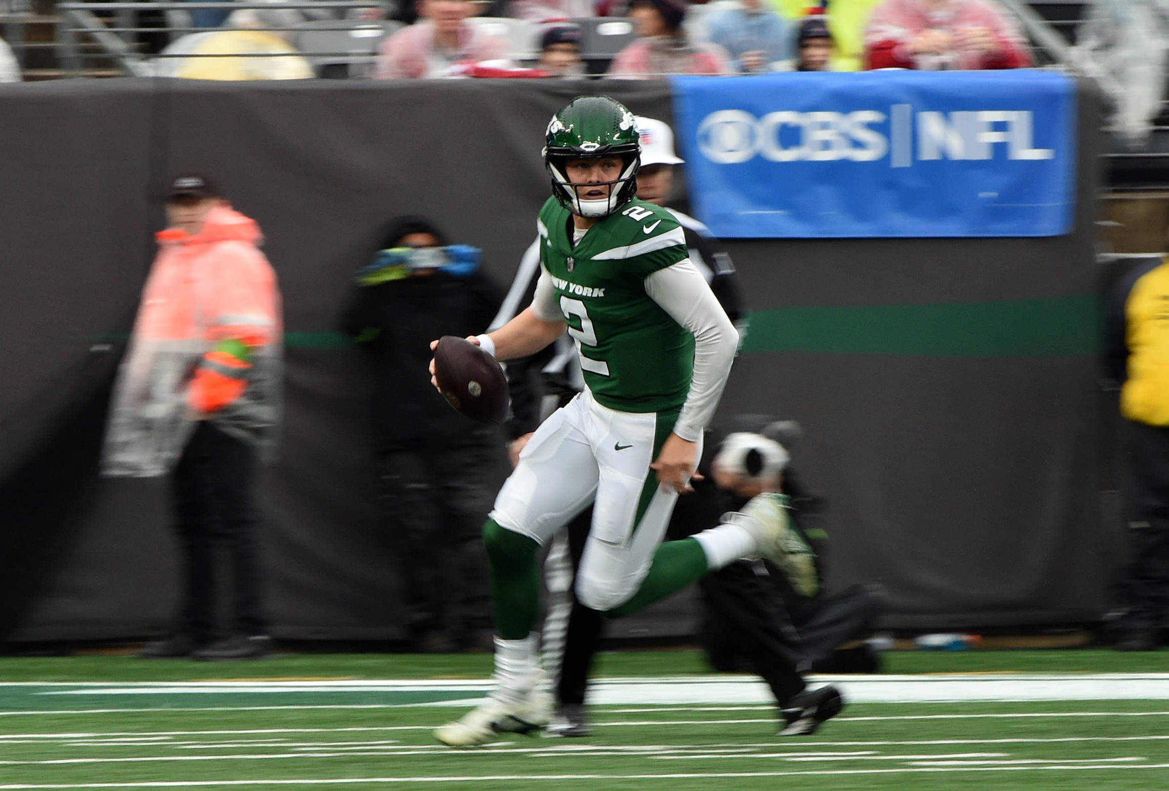 FootballR - NFL - Ein New Yorker Footballspieler in grüner Uniform, Zach Wilson, der mit einem Ball läuft und möglicherweise zum Spieler der Woche - Player of the Week - unter den QBs ernannt wurde.