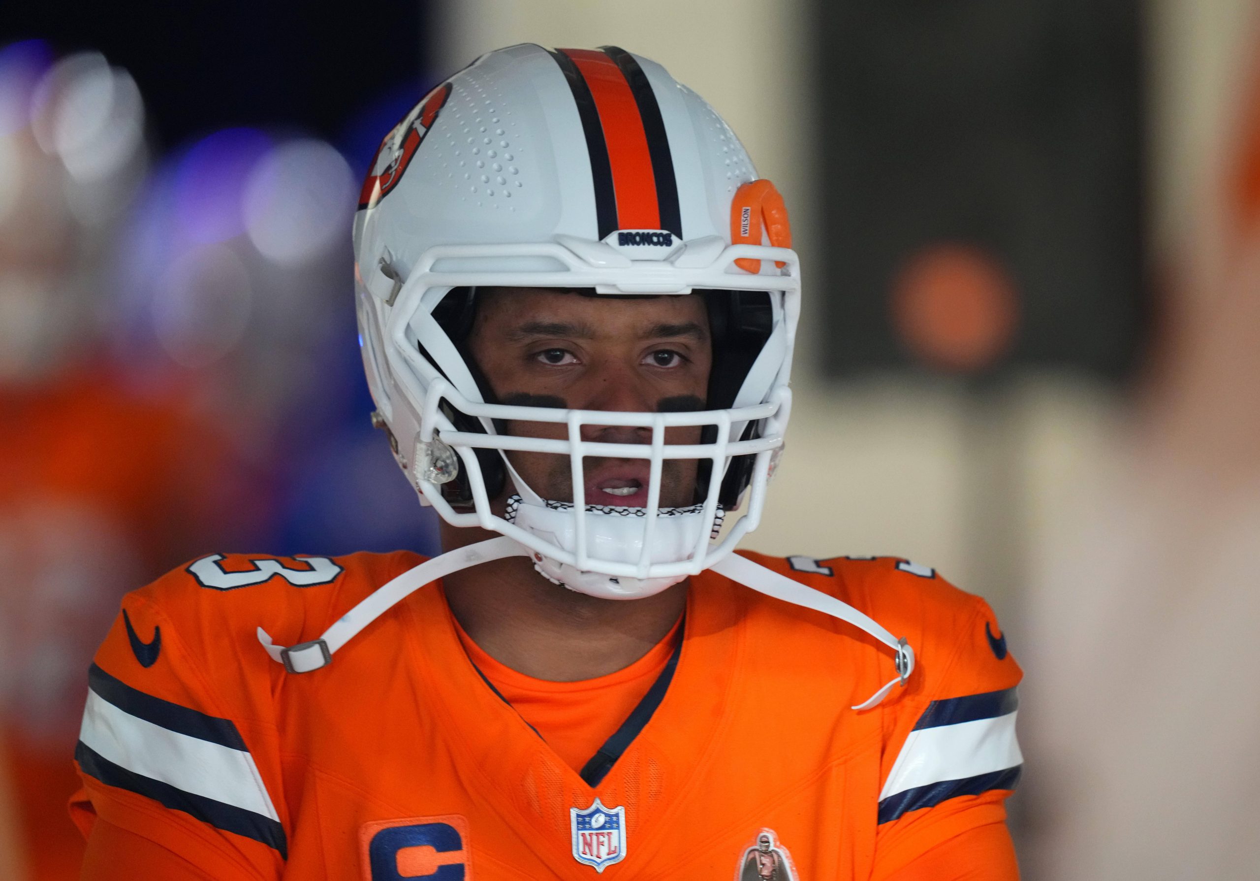 FootballR - NFL - Ein Spieler der Denver Broncos, Russell Wilson, der eine orange-weiße Uniform trägt.