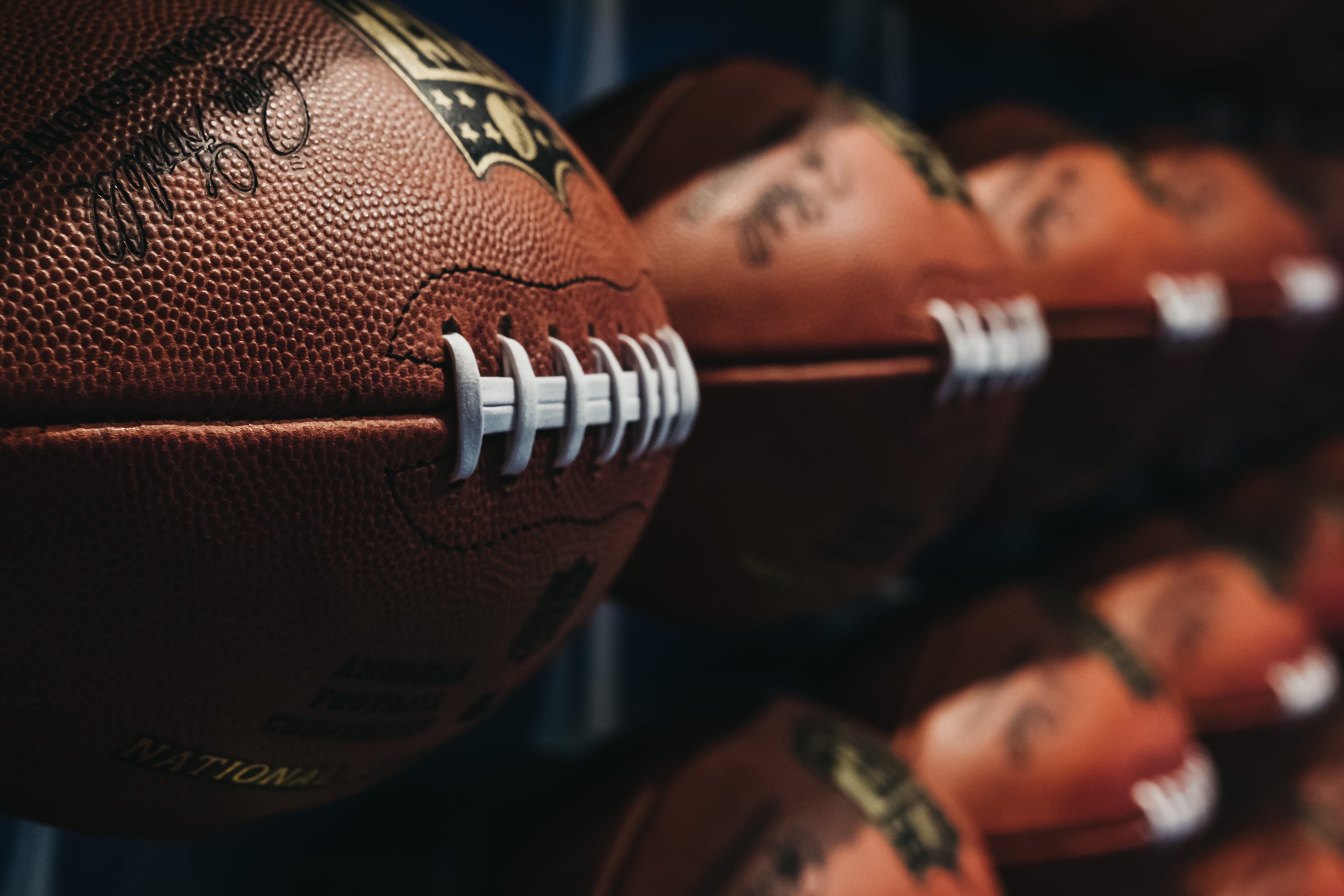 FootballR - NFL - Eine Reihe von NFL-Fußbällen an der Wand, die den NFL Spielplan 2024 für die kommende Saison zeigen. NFL Schedule 2024
