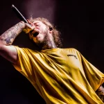 FootballR - NFL Super Bowl LVIII - Ein Mann in einem gelben Hemd, Post Malone, singt in ein Mikrofon.