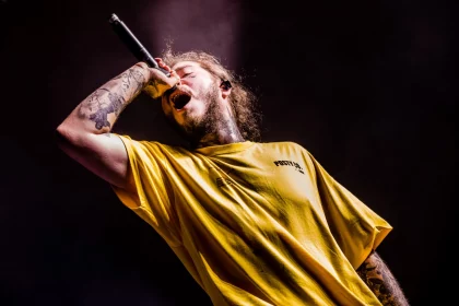 FootballR - NFL Super Bowl LVIII - Ein Mann in einem gelben Hemd, Post Malone, singt in ein Mikrofon.