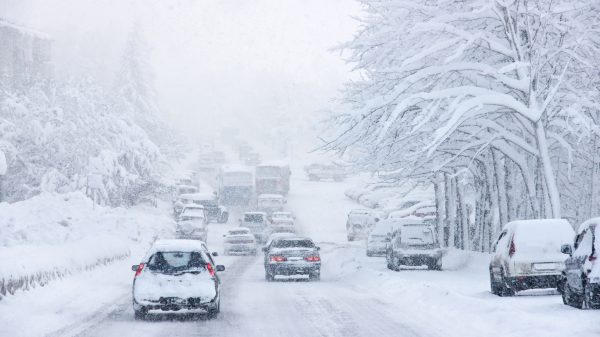 FootballR - NFL - Während eines Wintersturm in Buffalo fahren Autos eine schneebedeckte Straße entlang.