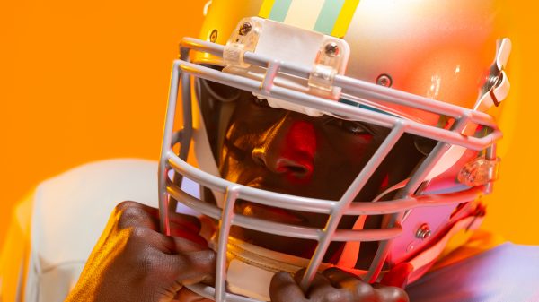 FootballR - NFL - NFL Free Agents 2024 - Ein Footballspieler mit Helm auf orangefarbenem Hintergrund.