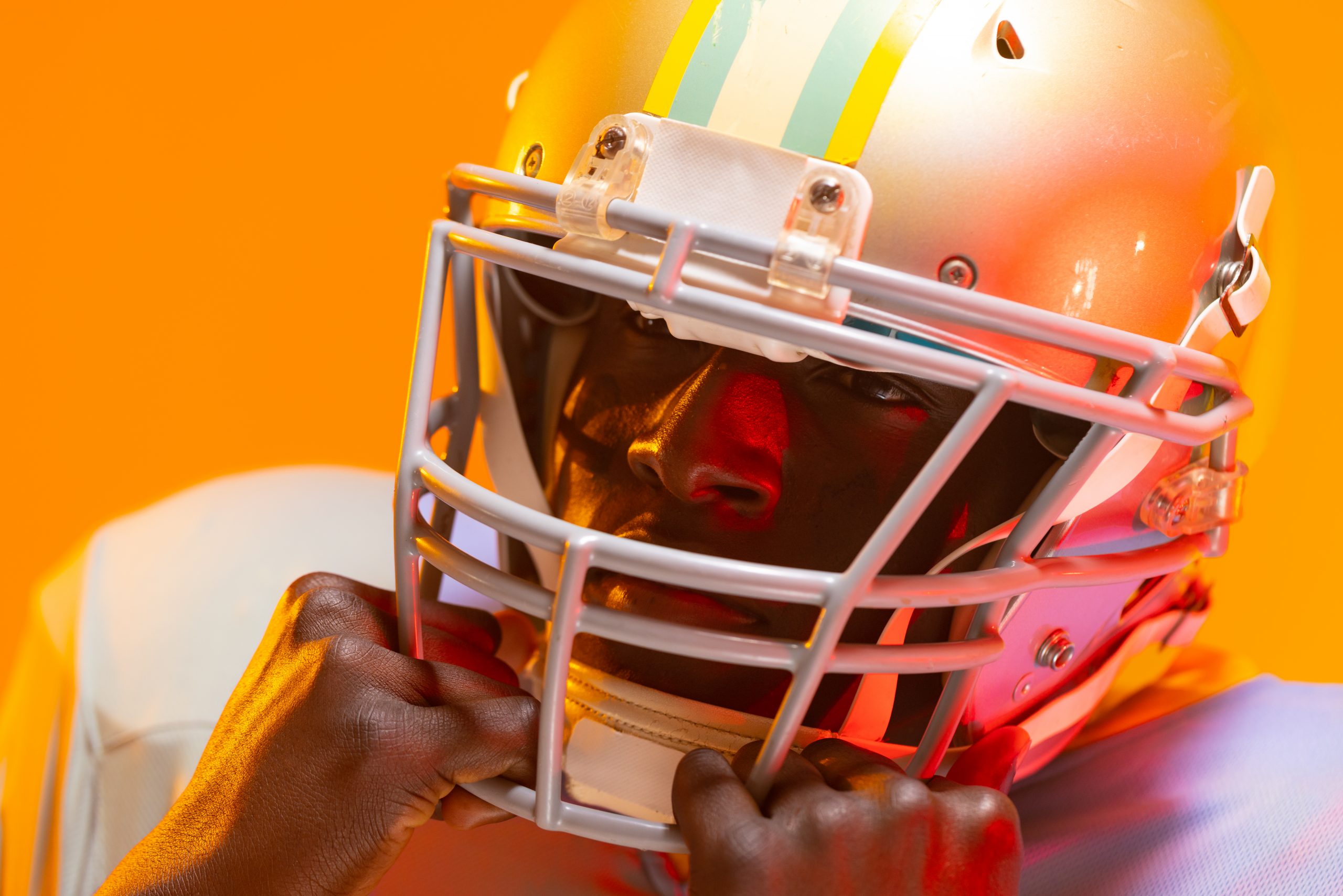 FootballR - NFL - NFL Free Agents 2024 - Ein Footballspieler mit Helm auf orangefarbenem Hintergrund.
