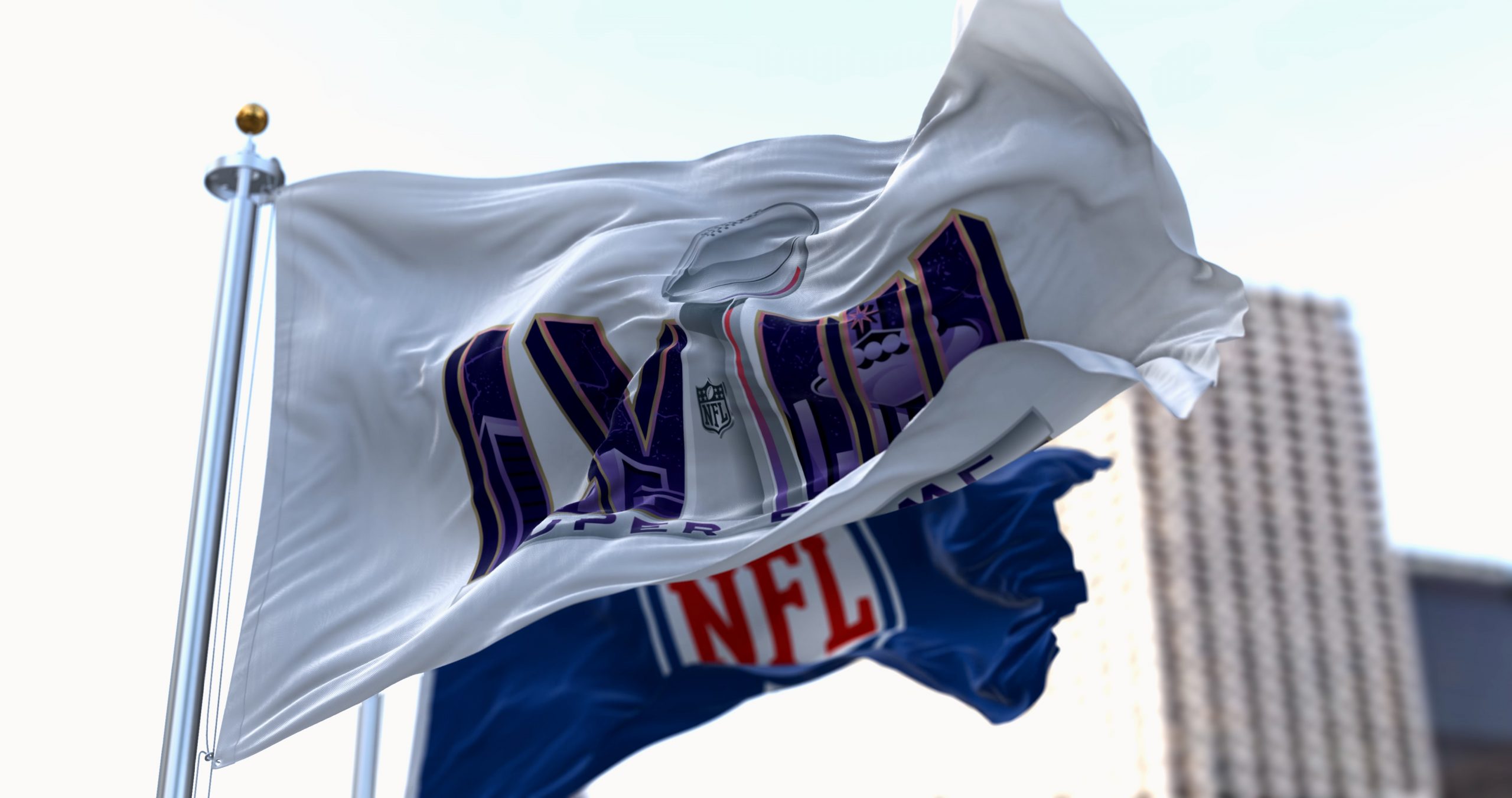 FootballR - NFL Playoffs - Die NFL-Flagge weht vor einem Gebäude und signalisiert die Spannung des Super Bowl LVIII.