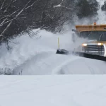 FootballR - NFL - Ein Schneepflug räumt eine verschneite Straße. Spielverschiebung wegen Wetter