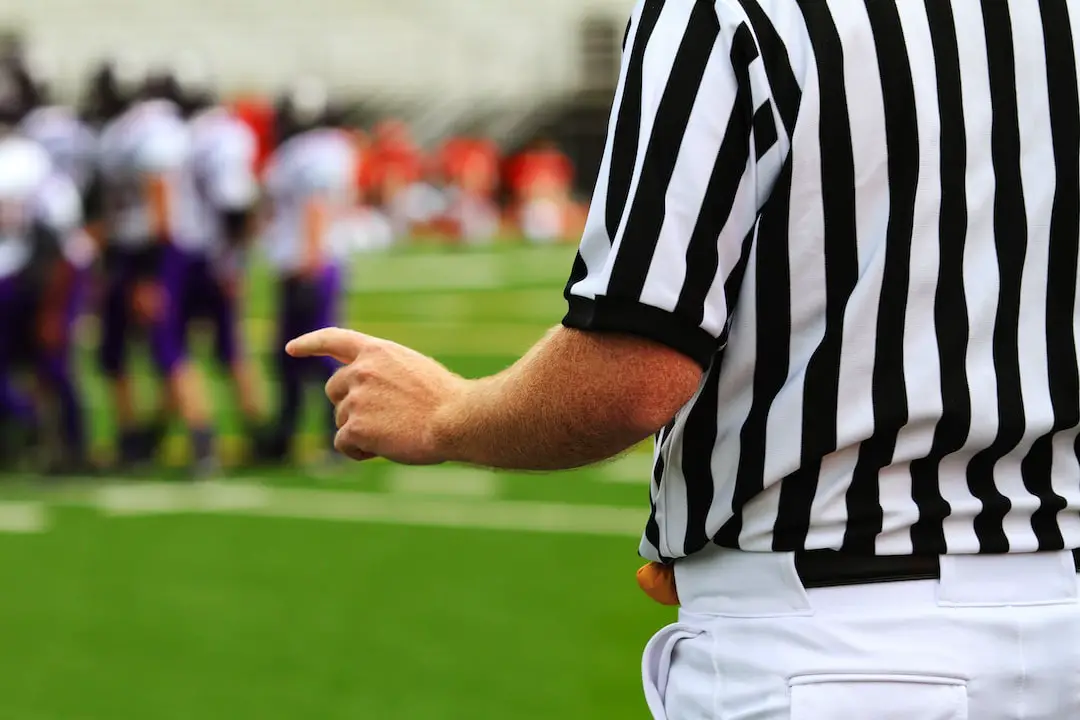 FootballR - NFL - Ein Schiedsrichter zeigt auf eine Fußballmannschaft auf dem Spielfeld.