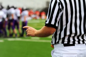 FootballR - NFL - Ein Schiedsrichter zeigt auf eine Fußballmannschaft auf dem Spielfeld.