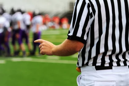 FootballR - NFL - Ein Schiedsrichter zeigt auf eine Fußballmannschaft auf dem Spielfeld.