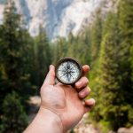 FootballR - NFL - Eine Person hält einen Kompass vor einem Wald.