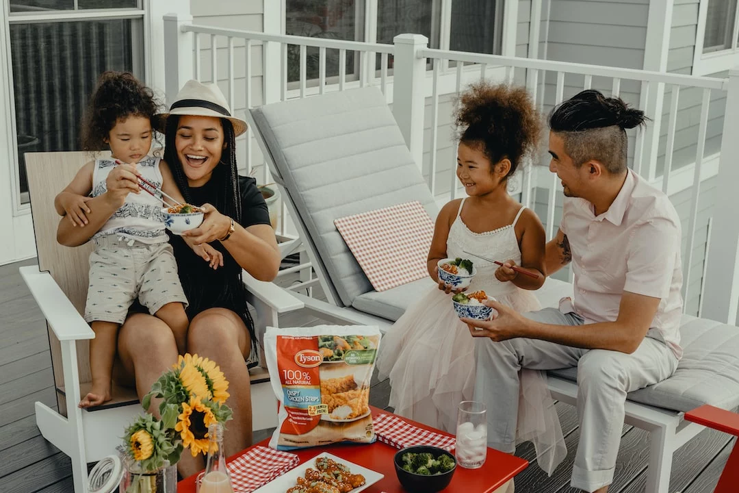 FootballR - NFL - Eine Familie sitzt auf einer Veranda und isst Essen.