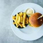 FootballR - NFL - Ein Burger und Pommes frites auf einem weißen Teller.
