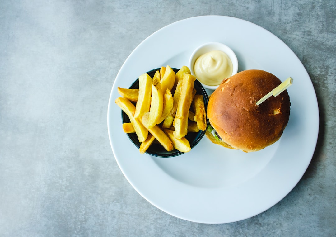 FootballR - NFL - Ein Burger und Pommes frites auf einem weißen Teller.