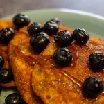FootballR - NFL - Pfannkuchen mit Blaubeeren und Sirup auf einem Teller.