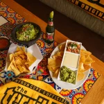 FootballR - NFL - Diese Beschreibung wurde automatisch generiert. Guacamole, Chips und Salsa auf einem Tisch.